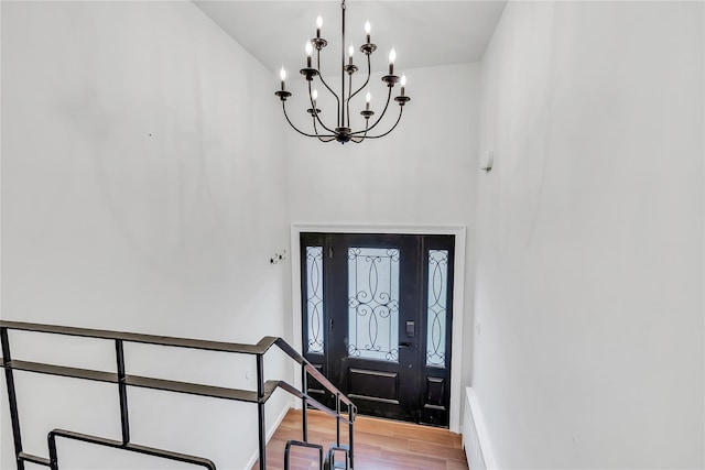 entrance foyer featuring a chandelier, light wood-style flooring, a high ceiling, and baseboards