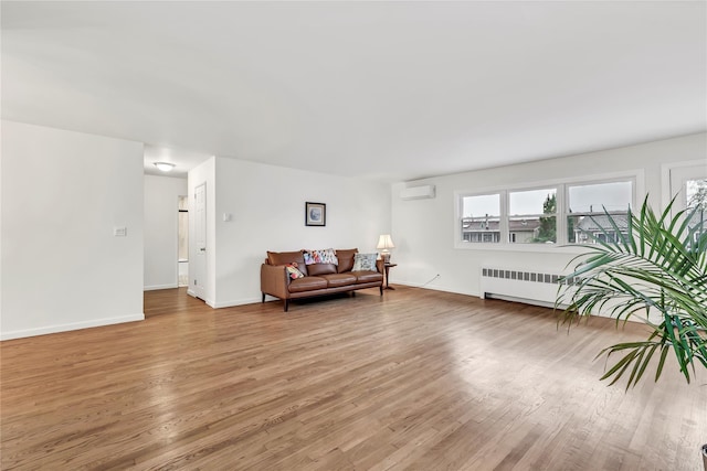 living area featuring radiator, a wall unit AC, light wood-style floors, and baseboards
