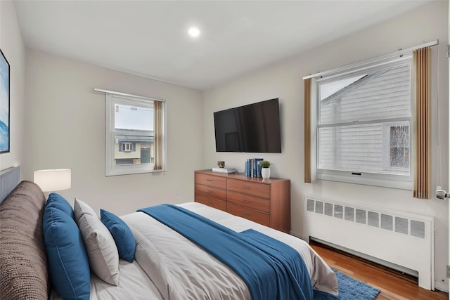bedroom featuring radiator, wood finished floors, and recessed lighting