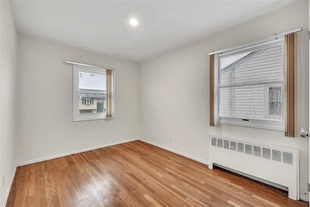 spare room featuring radiator, wood finished floors, and baseboards