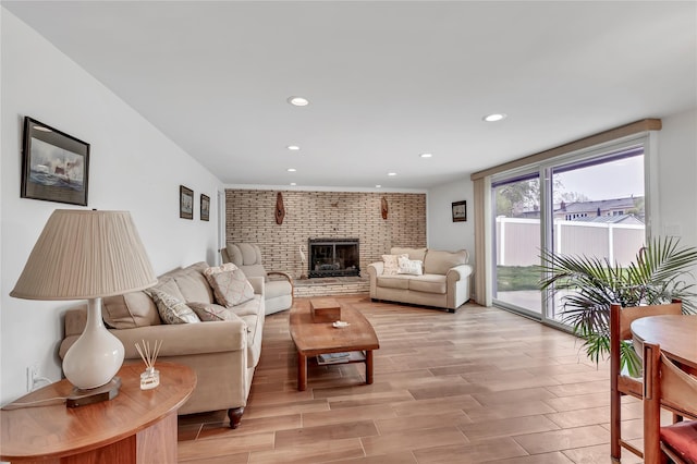 living room with light wood-style floors, recessed lighting, and a brick fireplace