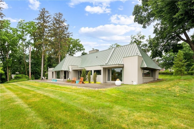 back of house with a yard, metal roof, and a standing seam roof