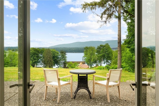 exterior space with a water and mountain view, a patio, and a lawn