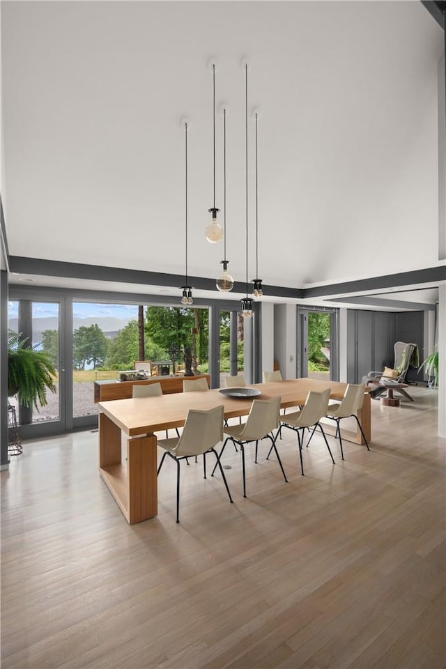 dining space featuring light wood-style flooring and a towering ceiling