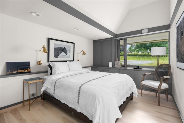 bedroom featuring light wood finished floors, baseboards, and lofted ceiling
