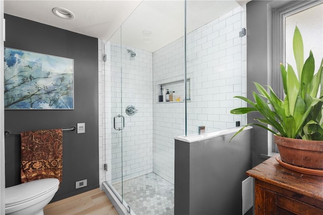 bathroom with vanity, baseboards, toilet, a shower stall, and wood finished floors
