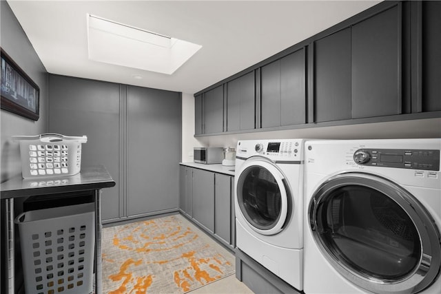 washroom featuring cabinet space, washing machine and clothes dryer, and a skylight