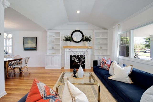 living room featuring built in features, light wood-style flooring, lofted ceiling, a premium fireplace, and baseboards