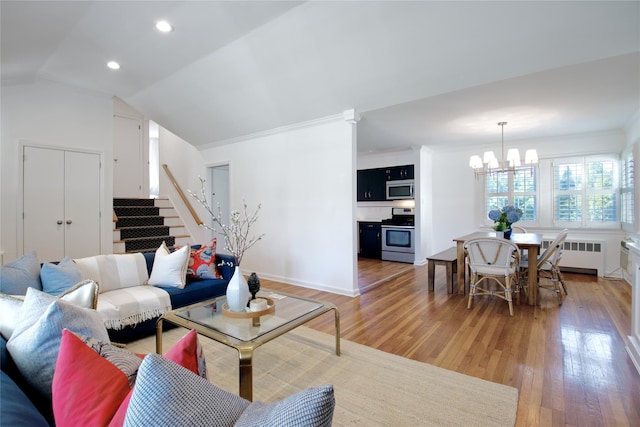 living room with radiator, a notable chandelier, light wood-style floors, and lofted ceiling