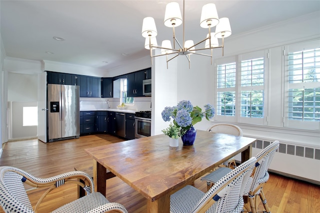 dining room with a chandelier, radiator heating unit, ornamental molding, and light wood finished floors