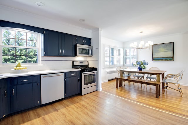 kitchen featuring a notable chandelier, light wood-style floors, stainless steel appliances, radiator heating unit, and blue cabinets