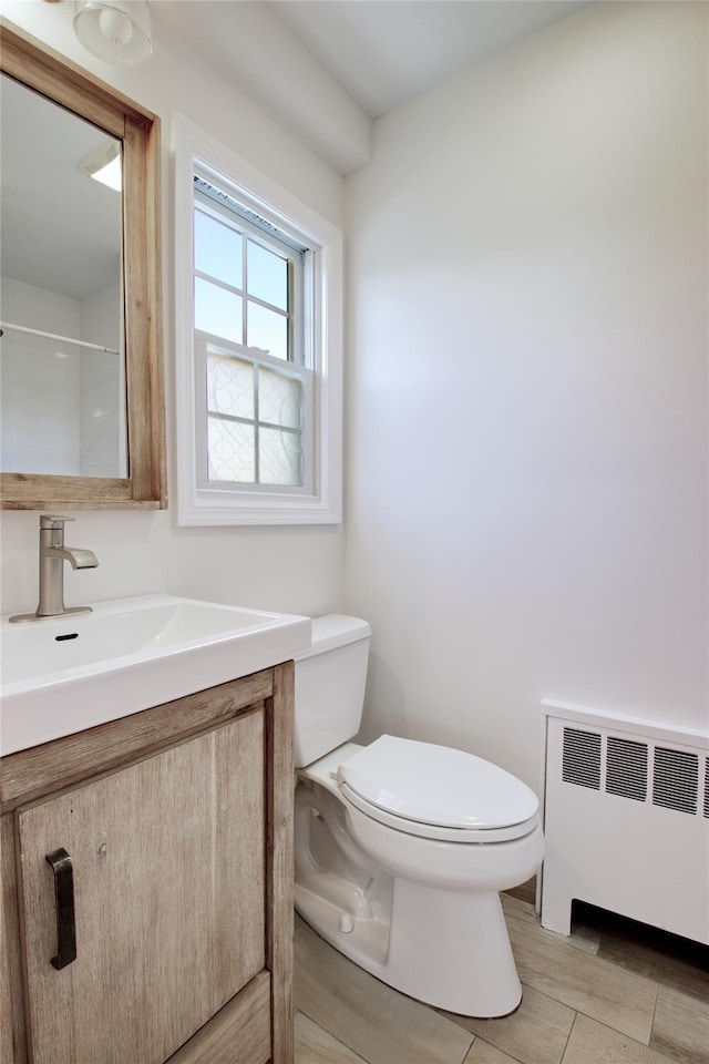 bathroom featuring toilet, radiator heating unit, and vanity