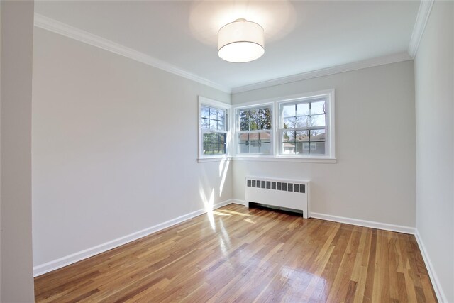 unfurnished room featuring ornamental molding, baseboards, radiator, and wood finished floors