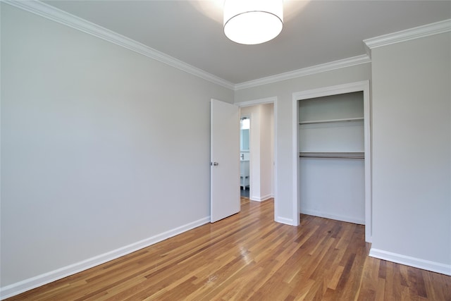 unfurnished bedroom with a closet, light wood-style flooring, baseboards, and crown molding