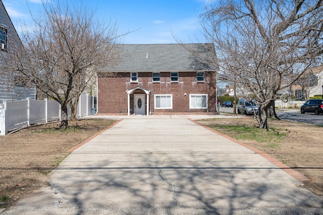 208 Newport Rd, Uniondale, NY 11553 - colonial home with concrete driveway, roof with shingles, fence, and brick siding