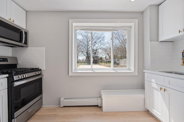208 Newport Rd, Uniondale, NY 11553 - kitchen with stainless steel appliances, a wealth of natural light, baseboard heating, and decorative backsplash