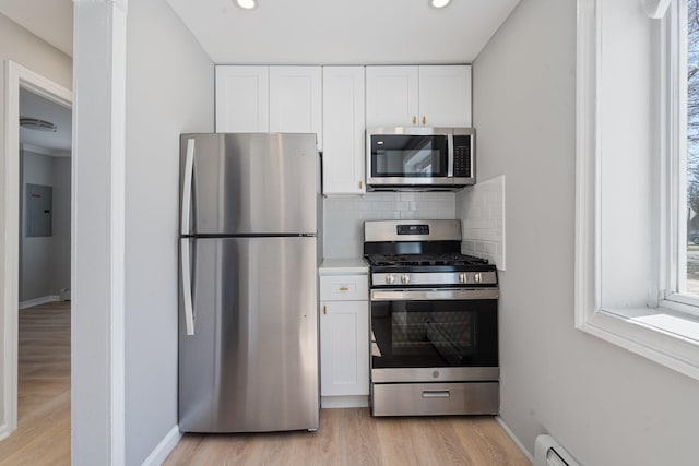 208 Newport Rd, Uniondale, NY 11553 - kitchen with light wood-type flooring, tasteful backsplash, white cabinetry, baseboard heating, and appliances with stainless steel finishes
