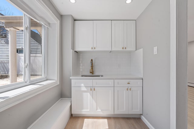 208 Newport Rd, Uniondale, NY 11553 - bar featuring light wood-style floors, indoor wet bar, recessed lighting, a sink, and backsplash