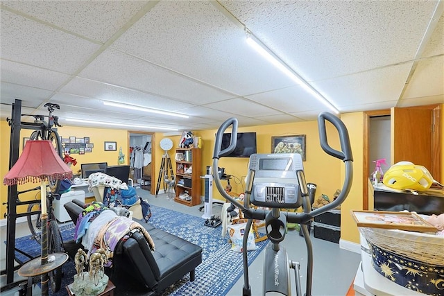 exercise room with a paneled ceiling and baseboards
