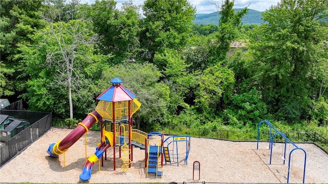 community playground featuring a mountain view and fence