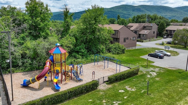 communal playground featuring a lawn, fence, and a mountain view