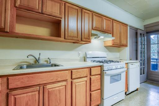 kitchen featuring a sink, light countertops, white appliances, and under cabinet range hood