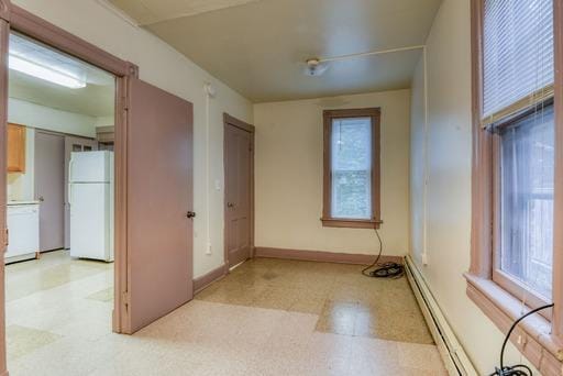 spare room featuring baseboards, light floors, and baseboard heating