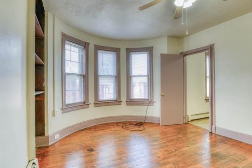 unfurnished room with baseboards, wood finished floors, a ceiling fan, and a healthy amount of sunlight