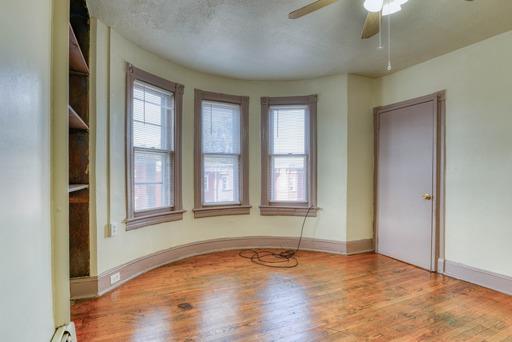 spare room with baseboards, wood finished floors, a ceiling fan, and a healthy amount of sunlight