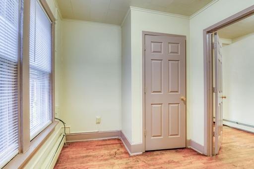 interior space featuring crown molding, a baseboard radiator, and light wood finished floors