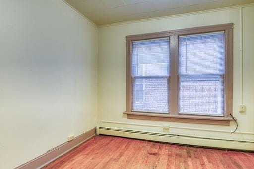 empty room with light wood-style flooring, a baseboard heating unit, baseboards, and ornamental molding