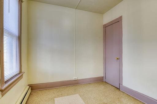 empty room featuring a baseboard heating unit and baseboards
