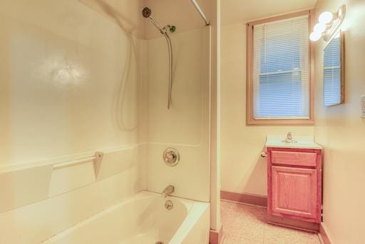 bathroom with washtub / shower combination, vanity, and baseboards