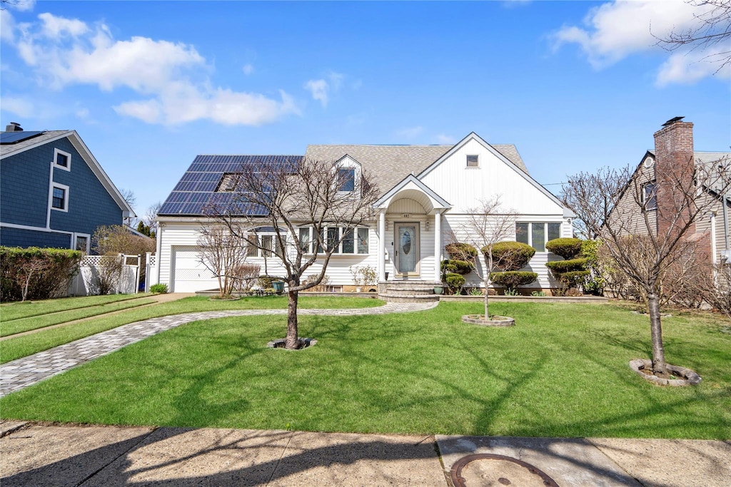 cape cod house featuring a garage, solar panels, and a front lawn