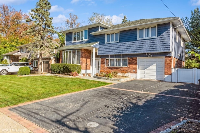 tri-level home with brick siding, aphalt driveway, fence, and a front yard