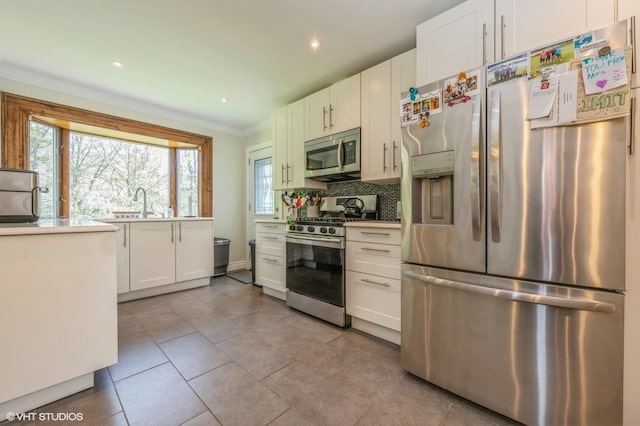 kitchen featuring crown molding, white cabinetry, backsplash, and stainless steel appliances