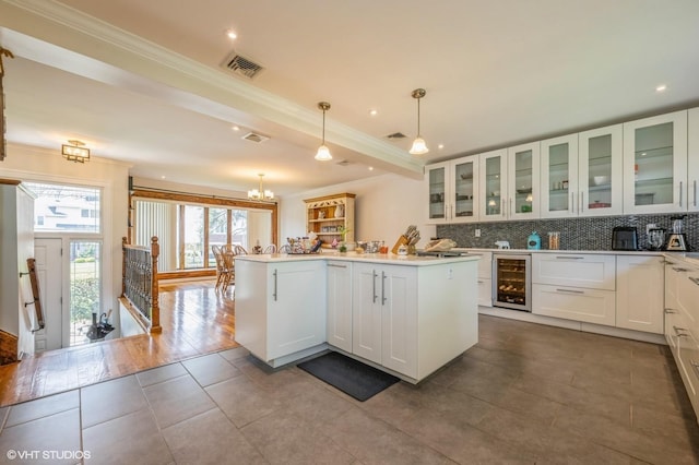 kitchen with backsplash, visible vents, a center island, beverage cooler, and ornamental molding