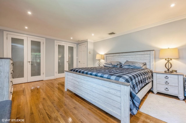 bedroom featuring crown molding, french doors, wood finished floors, and visible vents