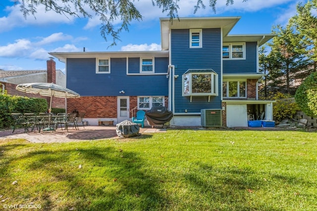 rear view of house featuring a lawn, a patio, cooling unit, and brick siding