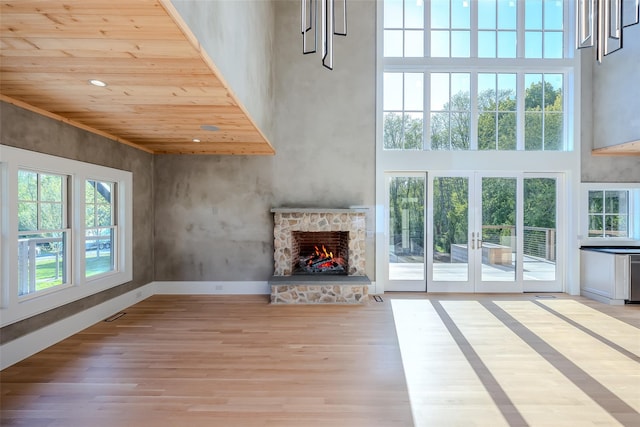 139A N Ferry Rd, Shelter Island, NY 11964 - unfurnished living room featuring a high ceiling, light wood finished floors, a stone fireplace, wooden ceiling, and baseboards