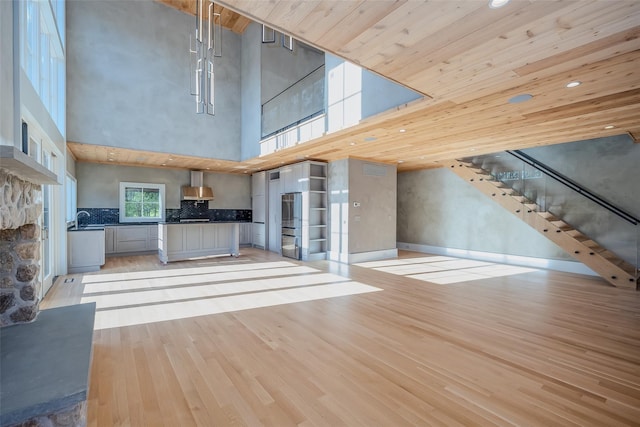 139A N Ferry Rd, Shelter Island, NY 11964 - unfurnished living room with light wood-style flooring, a sink, stairs, a towering ceiling, and recessed lighting