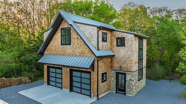 139A N Ferry Rd, Shelter Island, NY 11964 - view of front of house with a standing seam roof, concrete driveway, metal roof, a garage, and stone siding