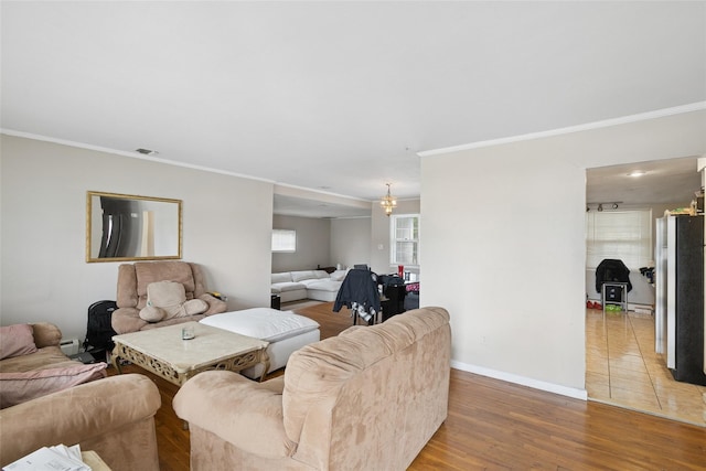 living area with wood finished floors, visible vents, baseboards, and ornamental molding