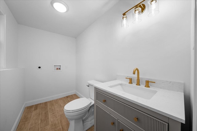 bathroom with toilet, vanity, wood finished floors, and baseboards