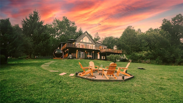 playground at dusk with a patio, a fire pit, a wooden deck, and a lawn