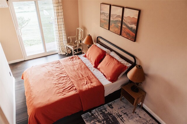 bedroom with access to exterior, wood finished floors, and baseboards