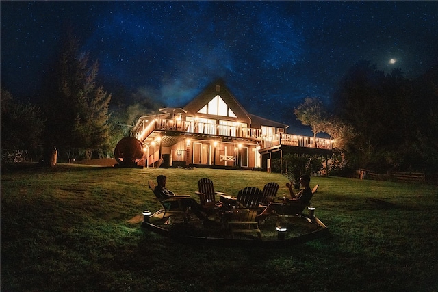 back of house at twilight featuring a deck, a lawn, and stairs