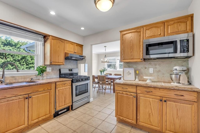 kitchen with a sink, under cabinet range hood, stainless steel appliances, backsplash, and light tile patterned flooring