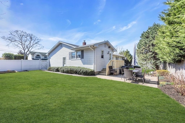 rear view of property featuring a yard, a fenced backyard, a patio area, and a chimney
