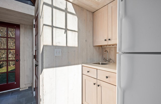 kitchen featuring a sink, light countertops, freestanding refrigerator, a wealth of natural light, and dark tile patterned floors